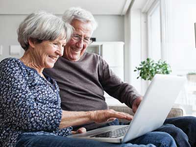 A man and woman sitting on a couch taking a health risk assessment on a laptop