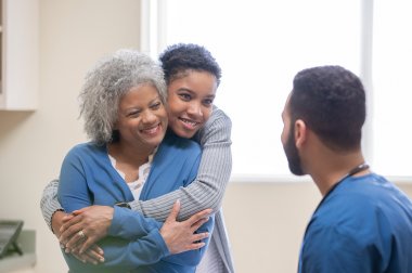 Two women hugging in front of doctor
