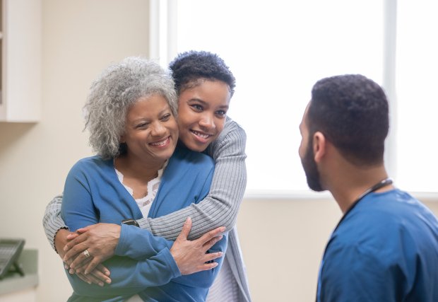 Two women hugging in front of doctor