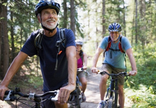 Two people smiling while riding bikes in the forest 