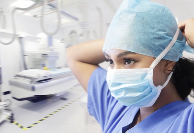 Female doctor putting on mask and scrub cap in operating room