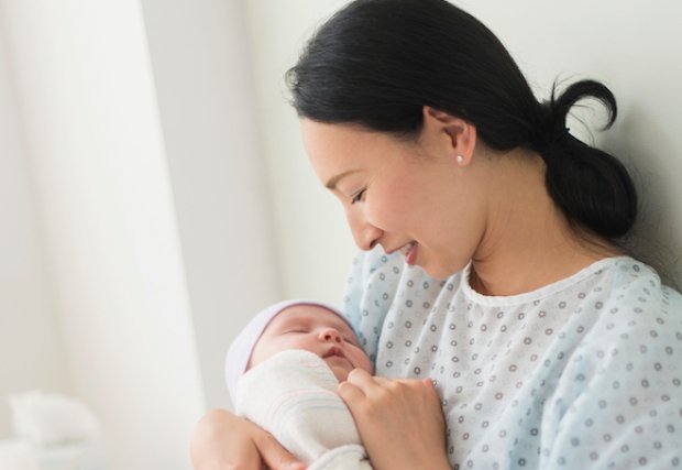 A mother holding her newborn baby in a hospital bed