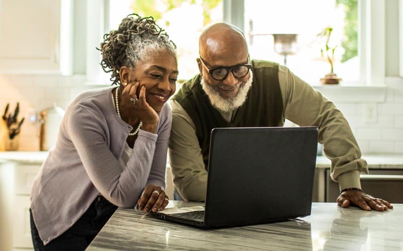 A couple in their kitchen taking a health risk assessment on their laptop