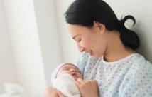 A mother holding her newborn baby in a hospital bed